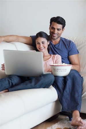 Portrait of a couple watching a movie while eating popcorn with a laptop Stock Photo - Budget Royalty-Free & Subscription, Code: 400-05742029