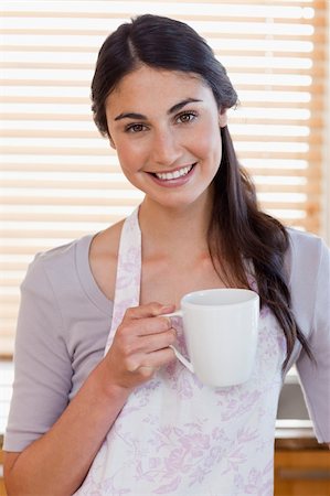 simsearch:400-04335902,k - Portrait d'une femme tenant une tasse de café dans sa cuisine Photographie de stock - Aubaine LD & Abonnement, Code: 400-05742713