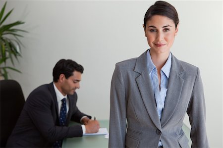 simsearch:400-04287075,k - Beautiful businesswoman posing while her colleague is working in an office Fotografie stock - Microstock e Abbonamento, Codice: 400-05742794