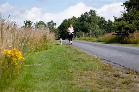 Sporty woman and dog jogging along a road in summertime Stock Photo - Budget Royalty-Free & Subscription, Code: 400-05742866