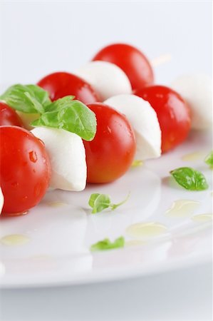 Cherry tomatoes and mozzarella on skewers, garnished with basil leaves and olive oil Stock Photo - Budget Royalty-Free & Subscription, Code: 400-05755145