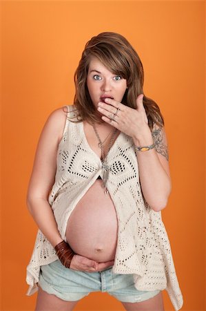 simsearch:400-05918412,k - Shocked pregnant Caucasian woman with hand on mouth over orange background Foto de stock - Royalty-Free Super Valor e Assinatura, Número: 400-05755772