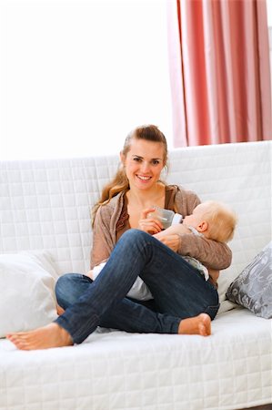 simsearch:400-05899075,k - Young mother sitting on sofa and feeding her baby Fotografie stock - Microstock e Abbonamento, Codice: 400-05750413