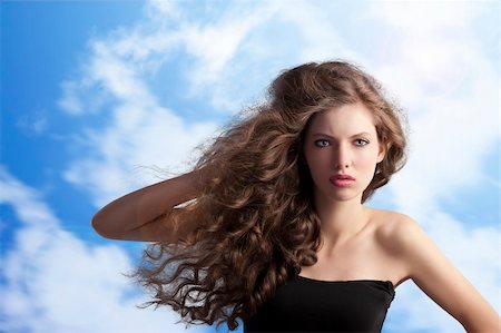 simsearch:400-04185400,k - beauty fashion portrait of a very young cute brunette with long curly hair with hairstyle flying in the wind on sky background Fotografie stock - Microstock e Abbonamento, Codice: 400-05750576