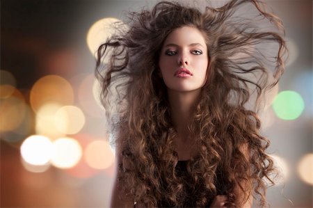 simsearch:400-04185400,k - beauty fashion portrait of a very young cute alluring brunette with long curly hair with hairstyle flying in the wind and city lights Fotografie stock - Microstock e Abbonamento, Codice: 400-05750579