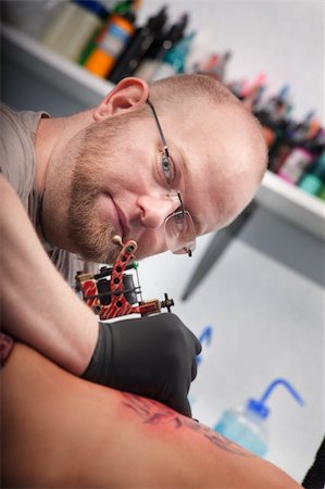 Bald Caucasian tattoo artist draws design on woman's back Fotografie stock - Microstock e Abbonamento, Codice: 400-05751357