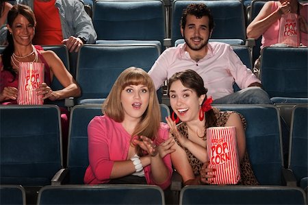 photo of theatre audience laughing - Friends with a bag of popcorn in theater Stock Photo - Budget Royalty-Free & Subscription, Code: 400-05751358