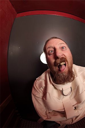 Photo of a insane man in his forties wearing a straitjacket leaning up against an asylum door.  Taken with a fisheye lens. Stock Photo - Budget Royalty-Free & Subscription, Code: 400-05751448