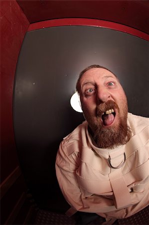 psiquiátrico - Photo of a insane man in his forties wearing a straitjacket leaning up against an asylum door.  Taken with a fisheye lens. Foto de stock - Super Valor sin royalties y Suscripción, Código: 400-05751448