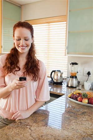 simsearch:400-05751258,k - Smiling woman writing text message in the kitchen Stock Photo - Budget Royalty-Free & Subscription, Code: 400-05751464