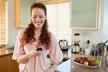 simsearch:400-05751258,k - Smiling woman in the kitchen writing text message Stock Photo - Budget Royalty-Free & Subscription, Code: 400-05751461