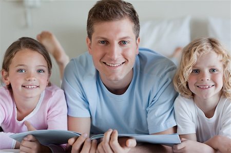 simsearch:400-05751566,k - Smiling father together with his children and a magazine Stock Photo - Budget Royalty-Free & Subscription, Code: 400-05751570