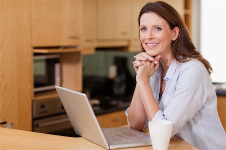 simsearch:400-04335902,k - Smiling woman in the kitchen with her laptop Photographie de stock - Aubaine LD & Abonnement, Code: 400-05751626