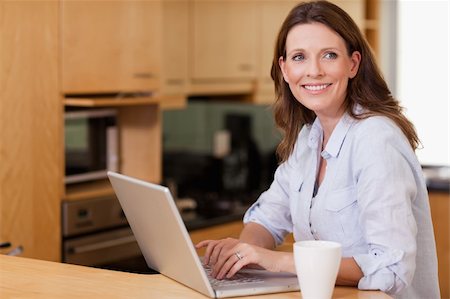 simsearch:400-04335902,k - Smiling woman in the kitchen with her notebook Stock Photo - Budget Royalty-Free & Subscription, Code: 400-05751627