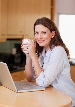 simsearch:400-05749531,k - Woman with laptop and a cup in the kitchen Stock Photo - Budget Royalty-Free & Subscription, Code: 400-05751634