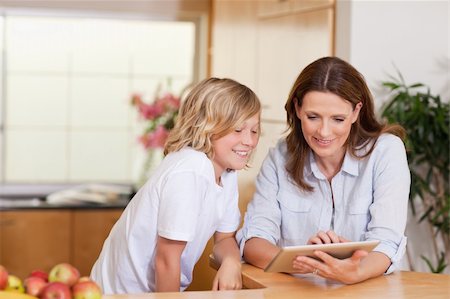 family tablet pc - Woman and son using tablet in the kitchen together Photographie de stock - Aubaine LD & Abonnement, Code: 400-05751639