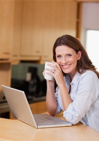simsearch:400-05741872,k - Smiling woman with cup next to laptop Foto de stock - Super Valor sin royalties y Suscripción, Código: 400-05751631