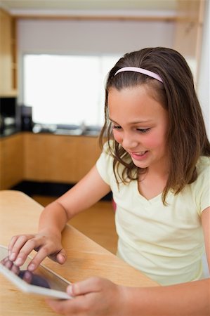 simsearch:6109-06194868,k - Little girl using tablet at the kitchen table Stock Photo - Budget Royalty-Free & Subscription, Code: 400-05751738