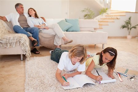 simsearch:400-05751679,k - Siblings doing their homework on the floor with parents behind them Stock Photo - Budget Royalty-Free & Subscription, Code: 400-05751850