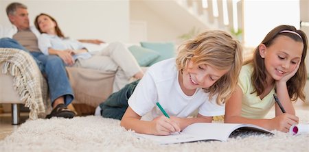 simsearch:400-05751676,k - Siblings doing their homework on the carpet with their parents behind them Stock Photo - Budget Royalty-Free & Subscription, Code: 400-05751852