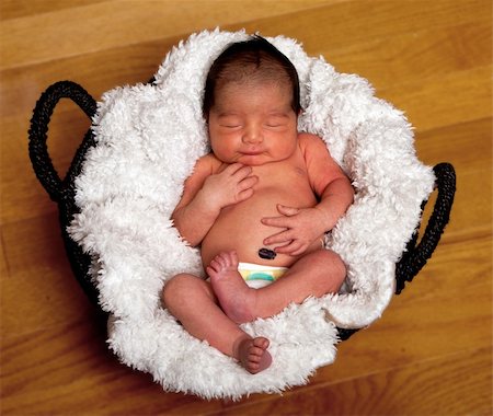 Cute baby asleep in basket with soft lining holding his belly. Stock Photo - Budget Royalty-Free & Subscription, Code: 400-05753330