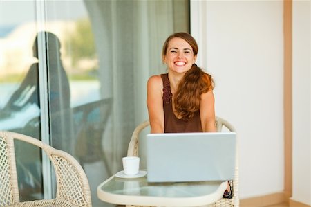 Happy young woman sitting on terrace with cup of coffee and laptop Stock Photo - Budget Royalty-Free & Subscription, Code: 400-05753454