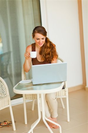 Smiling pretty woman having cup of tea and looking in laptop Stock Photo - Budget Royalty-Free & Subscription, Code: 400-05753453