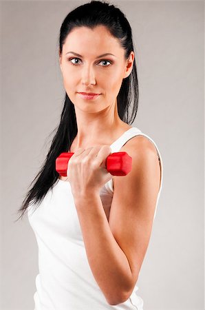 simsearch:400-04361224,k - sporty woman is exercising with red barbell on grey background and looking at camera Stock Photo - Budget Royalty-Free & Subscription, Code: 400-05875438