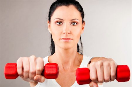 simsearch:400-04361224,k - sporty woman is holding two red barbells on grey background and looking at camera Stock Photo - Budget Royalty-Free & Subscription, Code: 400-05875439