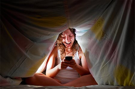 woman is sitting under cover in bed and chatting with friends via mobile phone Stock Photo - Budget Royalty-Free & Subscription, Code: 400-05875451