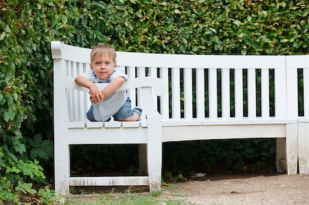 simsearch:400-06063102,k - Cute little boy sits on a bench in a park Fotografie stock - Microstock e Abbonamento, Codice: 400-05875554