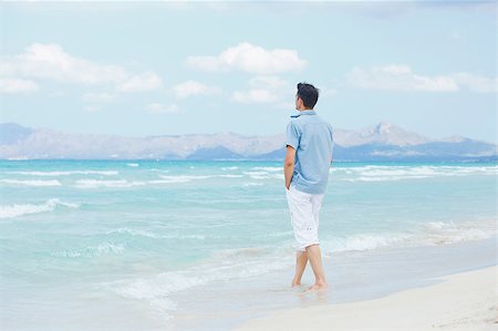 simsearch:400-04643781,k - Handsome young man walking near blue sea. Stock Photo - Budget Royalty-Free & Subscription, Code: 400-05875556