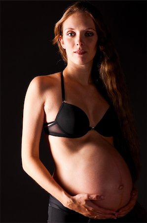 pregnant woman on black background is looking at camera Foto de stock - Super Valor sin royalties y Suscripción, Código: 400-05875638