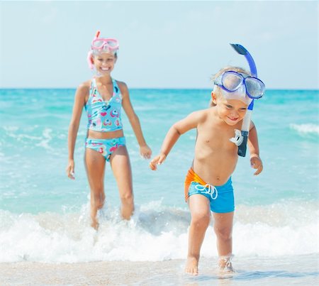 Happy young boy with snorkeling equipment on sandy tropical beach, his sister background. Stock Photo - Budget Royalty-Free & Subscription, Code: 400-05877663