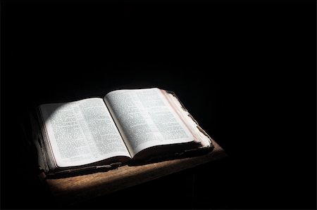 Old open bible lying on a wooden table in a beam of sunlight (not an isolated image) Shallow Depth of field â?? Focus on middle text Foto de stock - Super Valor sin royalties y Suscripción, Código: 400-05885459