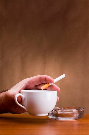 Hand holding a cigarette and a cup ashtray. Stock Photo - Budget Royalty-Free & Subscription, Code: 400-05887221