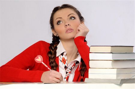 school girl holding pile of books - Young girl is sitting at the desk and reading the book Stock Photo - Budget Royalty-Free & Subscription, Code: 400-05880292