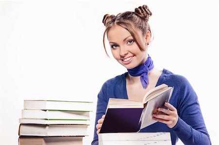 school girl holding pile of books - Young beautiful girl is sitting at the desk and reading the book Stock Photo - Budget Royalty-Free & Subscription, Code: 400-05880356