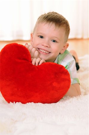 the child is lie on the floor with a red plush heart Fotografie stock - Microstock e Abbonamento, Codice: 400-05880504