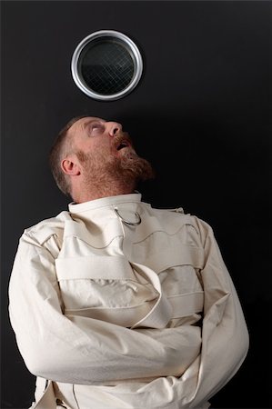 Photo of an insane man in his forties wearing a straitjacket crouched below the window of his cell. Stock Photo - Budget Royalty-Free & Subscription, Code: 400-05882345