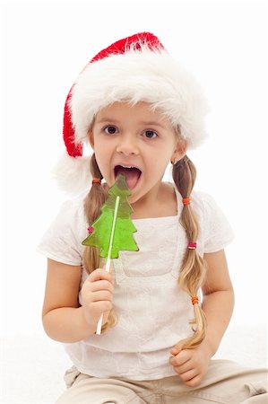 Happy Christmas girl licking a fir tree shaped candy - isolated Stock Photo - Budget Royalty-Free & Subscription, Code: 400-05882492