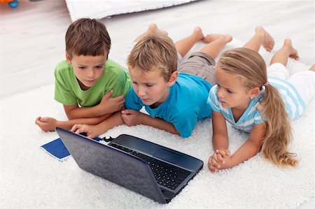 simsearch:400-04575374,k - Three kids looking at laptop computer screen laying on the floor Stock Photo - Budget Royalty-Free & Subscription, Code: 400-05882513