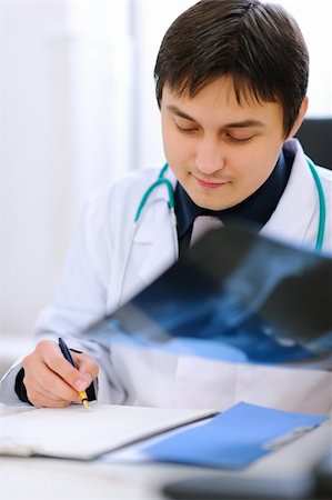 simsearch:400-07519214,k - Medical doctor analyzing patients roentgen and writing results in clipboard Stock Photo - Budget Royalty-Free & Subscription, Code: 400-05883647