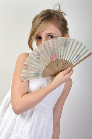 portrait of a beautiful elementary age girl hiding behind a fan Stock Photo - Budget Royalty-Free & Subscription, Code: 400-05894456