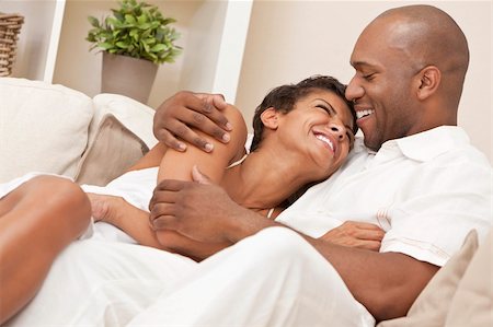 simsearch:400-04655735,k - A happy African American man and woman couple in their thirties sitting at home together cuddling & laughing. Stockbilder - Microstock & Abonnement, Bildnummer: 400-05894524