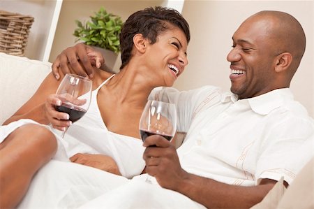 A happy African American man and woman couple in their thirties sitting at home together laughing and drinking glasses of red wine. Stock Photo - Budget Royalty-Free & Subscription, Code: 400-05894525