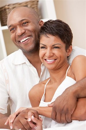 simsearch:400-04655736,k - A happy African American man and woman couple in their thirties sitting at home together smiling. Stockbilder - Microstock & Abonnement, Bildnummer: 400-05894536
