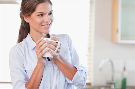 simsearch:400-04335902,k - Smiling woman holding a cup of tea in her kitchen Stock Photo - Budget Royalty-Free & Subscription, Code: 400-05894595