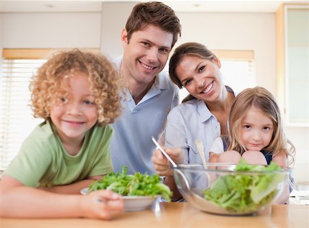 Smiling family preparing a salad together in their kitchen Stock Photo - Budget Royalty-Free & Subscription, Code: 400-05894674