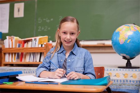 simsearch:400-05895060,k - Cute schoolgirl doing classwork while looking at the camera Photographie de stock - Aubaine LD & Abonnement, Code: 400-05894757